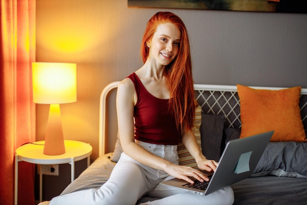 Mulher usando um laptop à noite sentada em um sofá no quarto ruim em casa