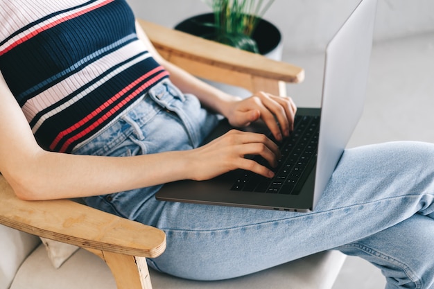 Mulher usando um laptop e digitando no teclado. Freelancer trabalhando distante em casa.