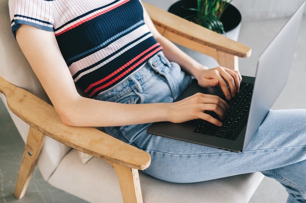 Mulher usando um laptop e digitando no teclado. Freelancer trabalhando distante em casa.