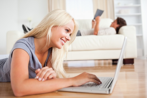 Mulher usando um laptop enquanto o marido está lendo