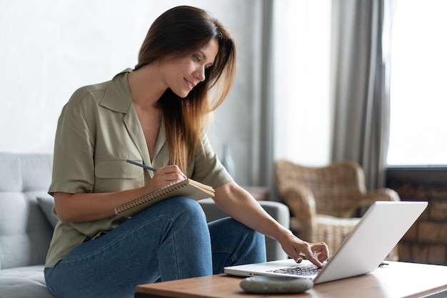 Mulher usando um laptop na sala de estar. Trabalhar em casa em regime de quarentena. Distanciamento social.