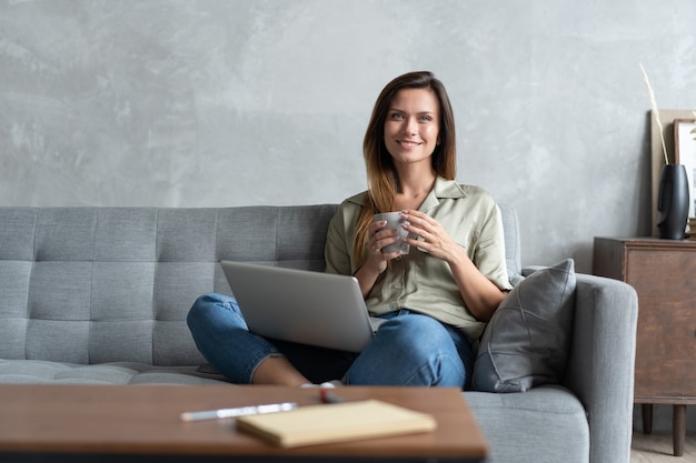 Mulher usando um laptop na sala de estar. trabalhar em casa em regime de quarentena. distanciamento social.