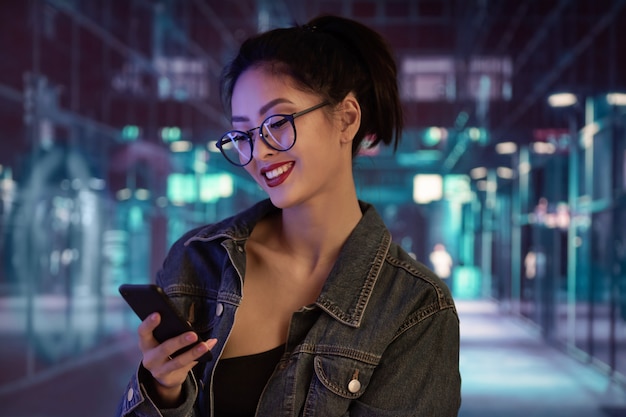 Foto mulher usando um smartphone na cidade à noite