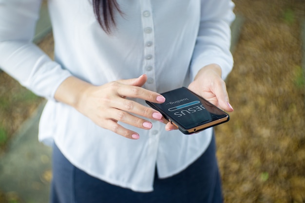 Mulher usar smartphone em casa. Barra de progresso Carregando com o texto: Jesus na tela do smartphone. Igreja conceito on-line.