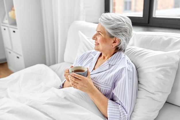 mulher velha com uma chávena de café na cama em casa