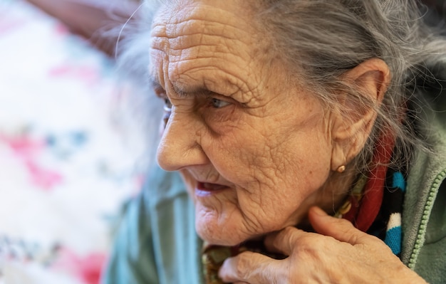 Mulher velha. Retrato de uma mulher muito velha e cansada em depressão, sentada dentro de casa na cama