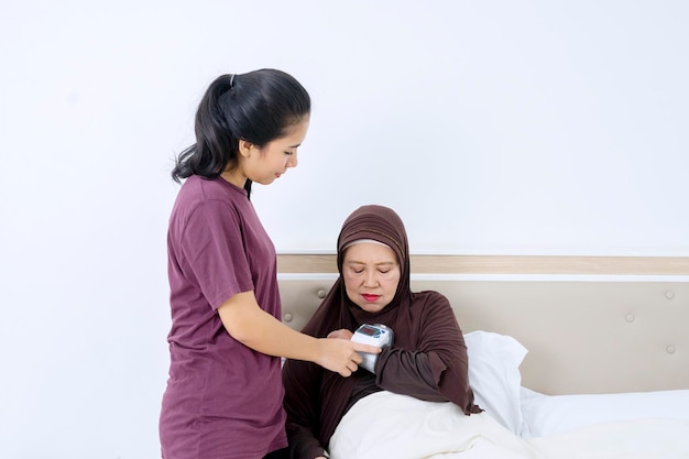 Mulher velha verificando-a saudável com máquina de pressão arterial