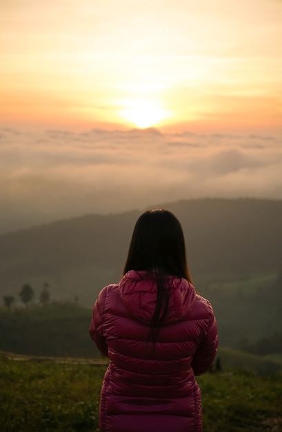 Mulher vendo o nascer do sol sozinha no topo da colina