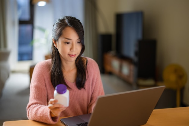 Mulher verifica o ingrediente do medicamento no computador portátil