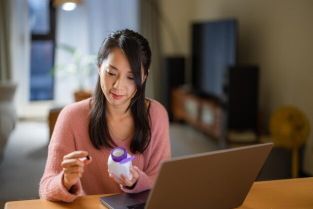 Mulher verifica o ingrediente do medicamento no computador portátil