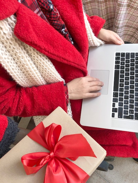 Mulher vestida com um casaco de pele vermelha usando Laptop na véspera de férias de Natal e ano novo.