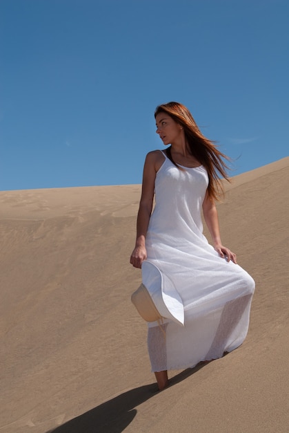 mulher vestida de branco apreciando as dunas de areia em um dia ensolarado de primavera ou verão