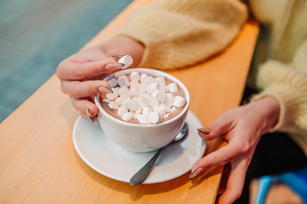 Mulher vestida de suéter quente, beba marshmallow com leite, café, cacau ou café com leite