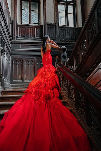 Mulher vestido vermelho vintage velho castelo linda princesa em vestido sedutor elegante caucasiana feminina história de conto de fadas escada escura