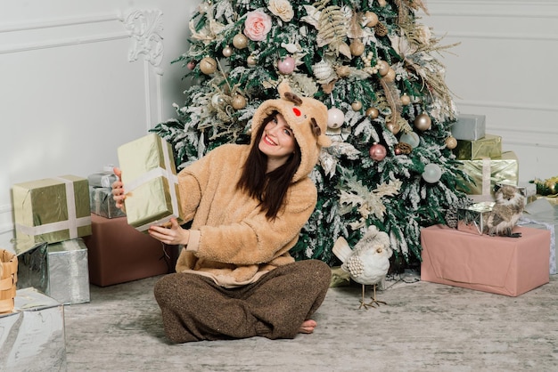 Mulher vestindo a árvore de Natal, sorrindo, sentada no interior do ano novo