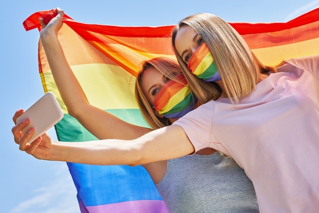 Mulher vestindo a bandeira lgbt ao ar livre tomando selfie. Foto de alta qualidade