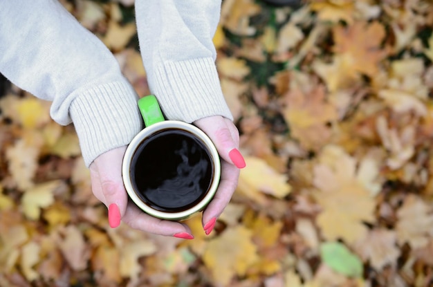 Mulher vestindo blusa branca, segurando uma xícara de café verde