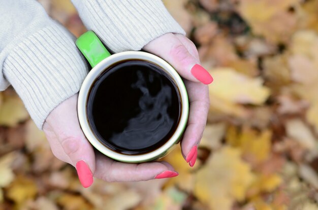 Mulher vestindo blusa branca, segurando uma xícara de café verde