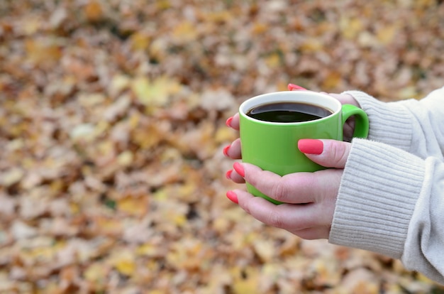 Mulher vestindo blusa branca, segurando uma xícara de café verde