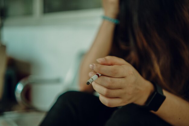 Mulher vestindo camisa preta estressando-se com o conceito de estilo de vida insalubre de cigarro de mão de trabalho