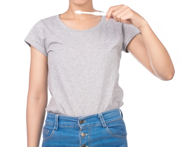 mulher vestindo camiseta cinza em branco, jeans usa escova de dentes isolada no fundo branco.