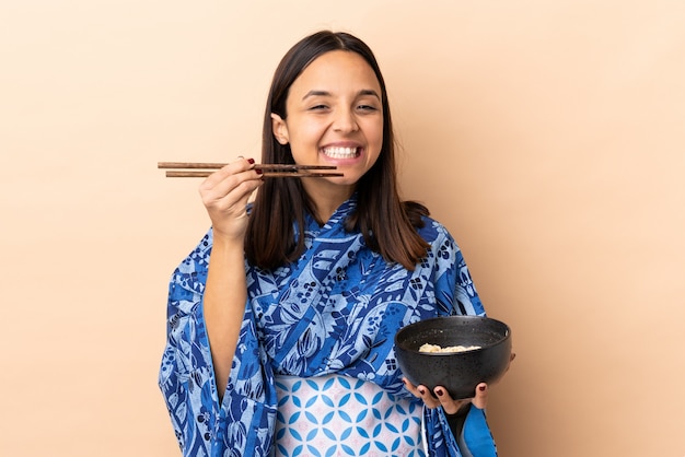 Foto mulher vestindo quimono e segurando uma tigela cheia de macarrão segurando uma tigela de macarrão com pauzinhos