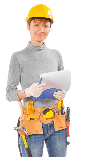 Mulher vestindo roupas de trabalho e ferramentas de construção segurando a prancheta com lençol branco e olhando para câmera isolada no fundo branco