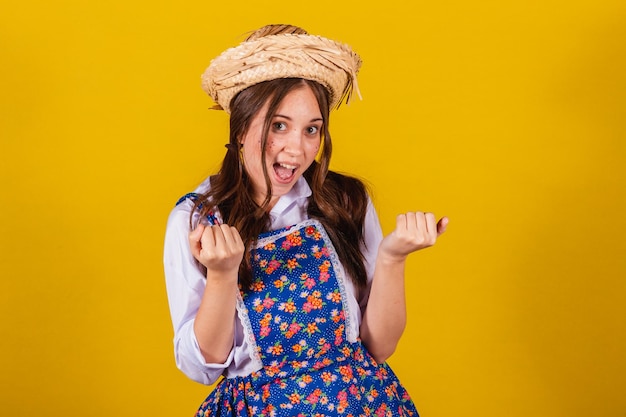 Mulher vestindo roupas típicas da Festa Junina chamando com as mãos convidando vir aqui