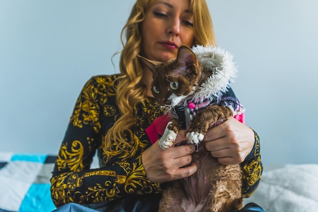 Mulher vestindo seu gato Devon Rex com roupas fofas cuidando de animais de estimação