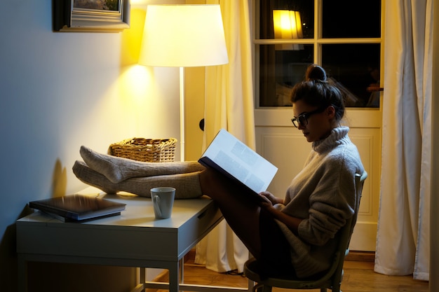 Mulher vestindo um suéter de lã quente está lendo livro