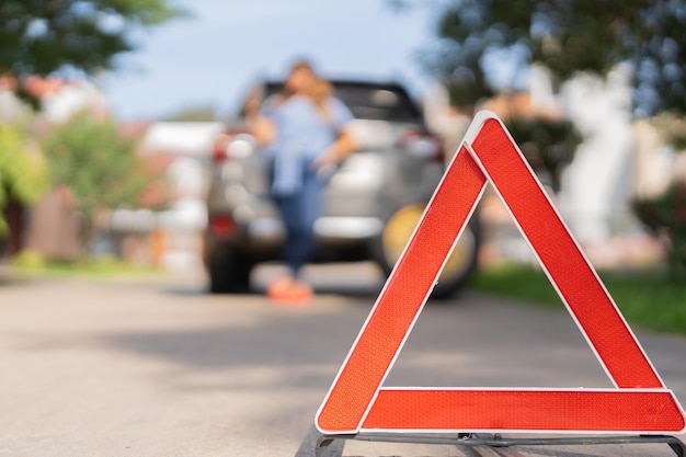 Foto mulher vestindo um triângulo de segurança esperando o rebocador pegar seu carro