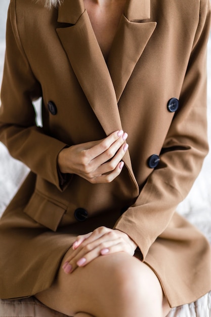 Mulher vestindo uma jaqueta marrom elegante de grandes dimensões com botões pretos no corpo nu. foto