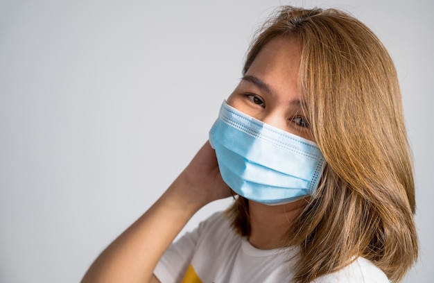 Foto mulher vestindo uma máscara protetora de higiene sobre o rosto em fundo branco,
