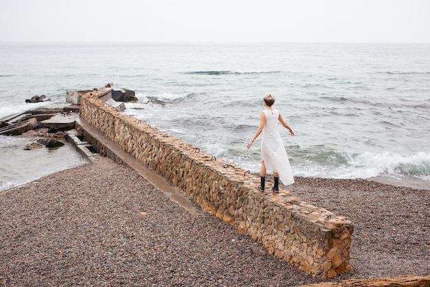 Mulher vestindo vestido andando perto do mar no outono