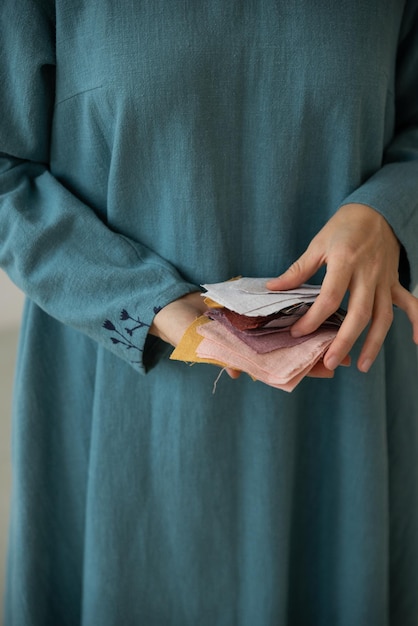 Mulher vestindo vestido azul segurando preços de exemplos de tecido de linho colorido Colheita de alfaiate feminina