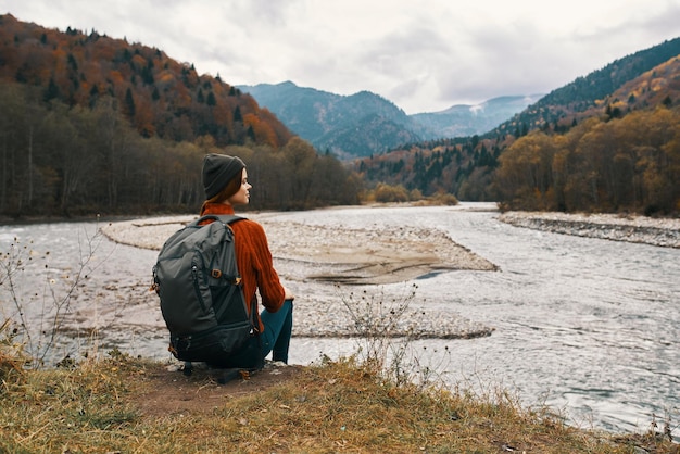 Foto mulher viaja nas montanhas perto do rio na natureza e olha para as montanhas ao longe