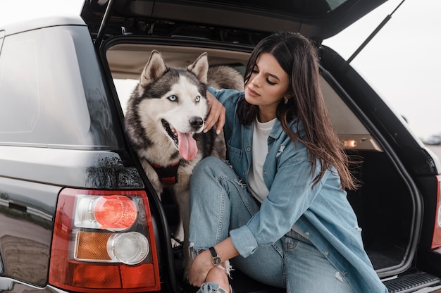 Foto mulher viajando de carro com seu adorável cachorro husky