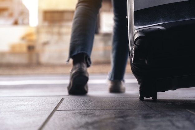 Mulher viajando e arrastando uma bagagem preta ao ar livre