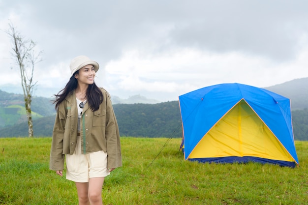 Mulher viajando feliz curtindo e relaxando perto da barraca do acampamento