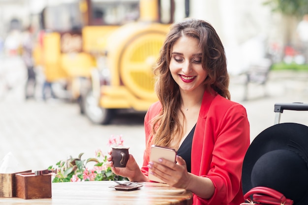 Mulher viajando olhando em smartphone sentado no café ao ar livre.