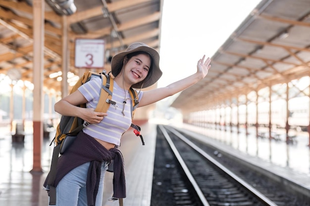 Mulher viajante asiática bonita carregando uma mala esperando o trem na estação ferroviária