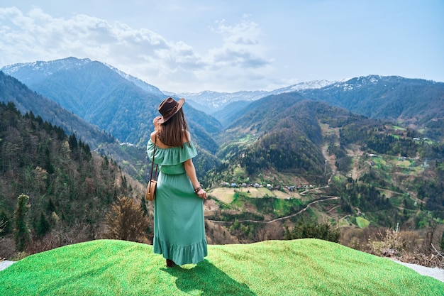 Mulher viajante chique boho usando vestido longo e chapéu viajando sozinha nas montanhas