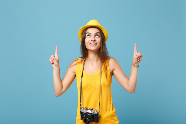 Mulher viajante com roupas casuais de verão amarelo e chapéu com câmera fotográfica azul