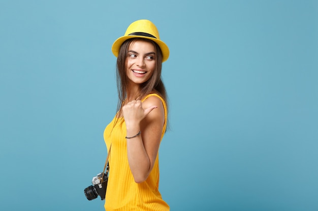 Mulher viajante com roupas casuais de verão amarelo e chapéu com câmera fotográfica azul