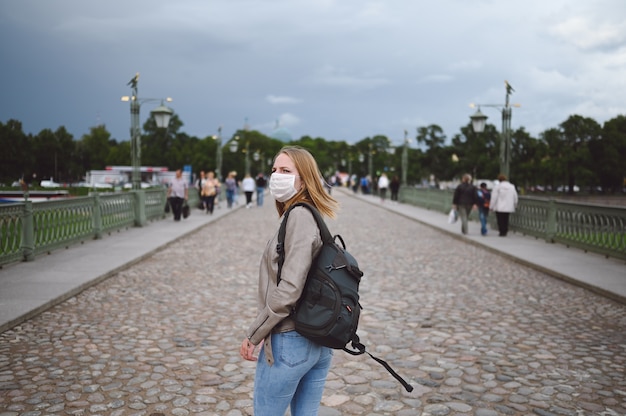 Mulher viajante com uma mochila e uma máscara médica