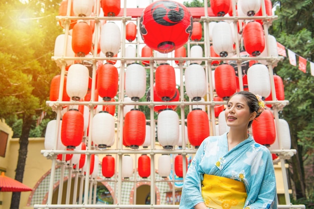 mulher viajante sorridente em frente ao grupo de decoração de lanterna desfrutar do festival japonês e vestindo quimono tradicional do japão durante a viagem.