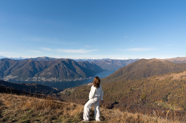 Mulher viajante vestida de branco no topo da montanha admirando a paisagem do lago di como itália