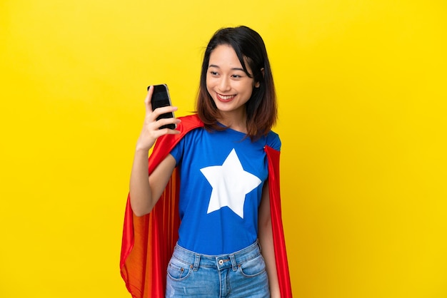 Mulher vietnamita super-heroína isolada em fundo amarelo fazendo uma selfie