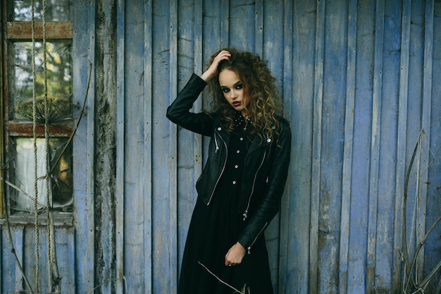 Mulher vintage como bruxa posando no cenário de um lugar abandonado na véspera do Halloween