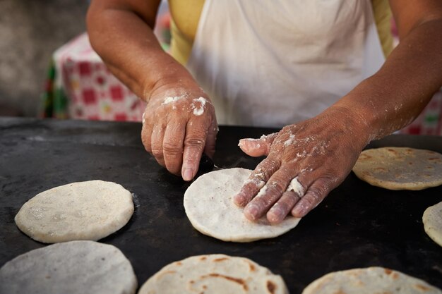 Foto mulher virando uma tortilha de milho com uma espátula em uma grelha quente